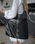 person with black mesh and glossy vinyl sporty tote bag with black leather and webbing details.