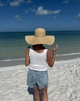 Person wearing a wide-brimmed hat standing on a beach.