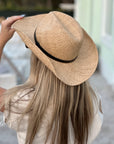 Person wearing the Raffie Straw Western Hat with black leather band