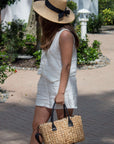 Person carrying a medium sized hyancinth straw bag with black leather handles and black crossbody strap