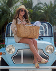 Person holding the Fullerton Straw Tote - a large natural hyacinth straw tote with matching leather handles