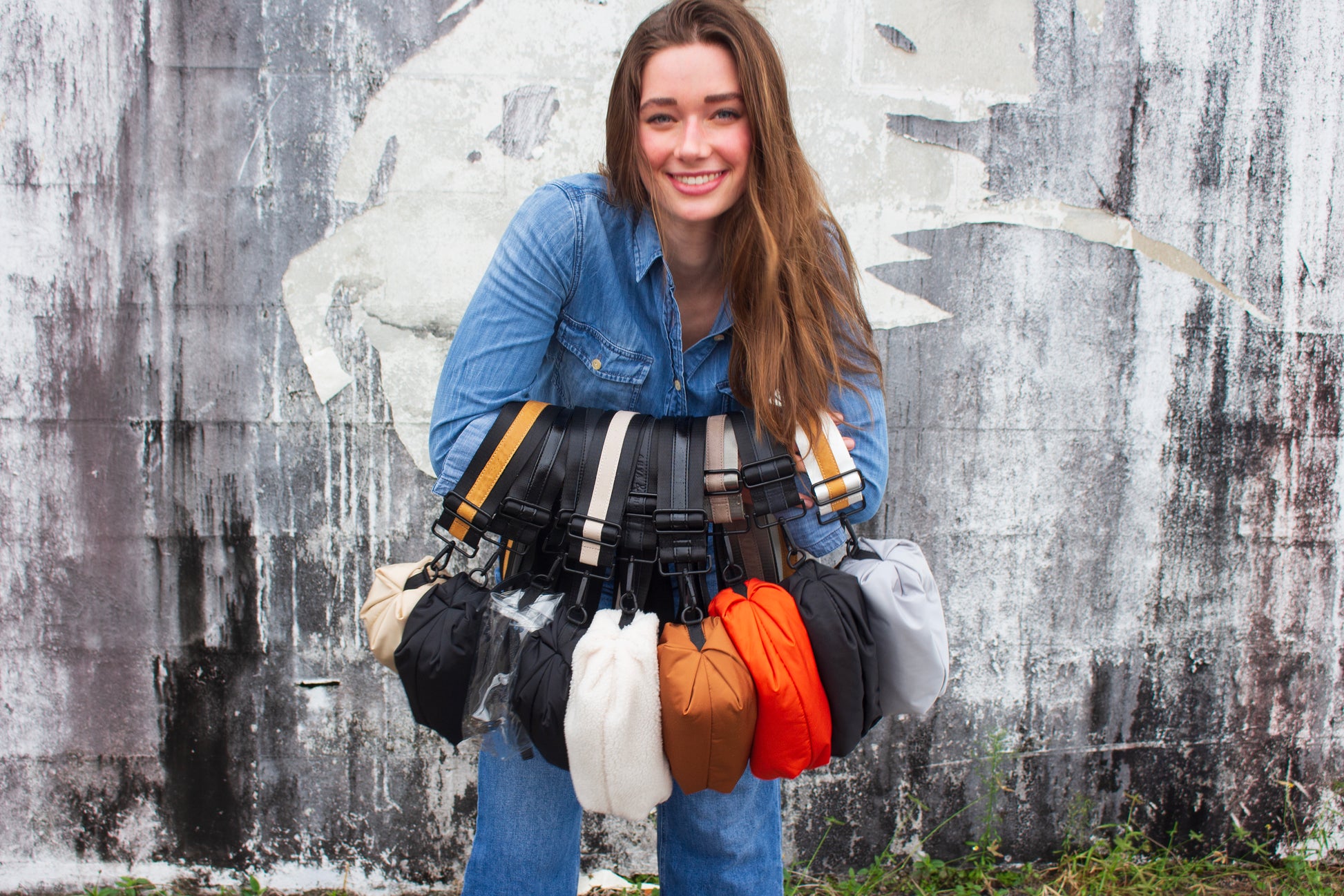 Person holding the collection of Orlando Crossbody Belt bags in 9 colors. 