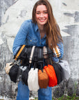 Person holding the collection of Orlando Crossbody Belt bags in 9 colors.