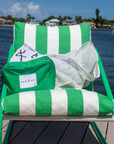 Green and white striped chair with accessories on a dock by water