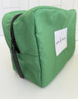 Green toiletry bag with a black zipper on a white background