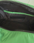 Close-up of a green bag with a visible brand logo on a tiled floor.
