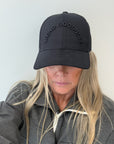 Person wearing a black cap with 'LIVING GOODNESS' text on a plain background