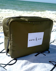 Green bag with 'Anya & Niki' label on a sandy beach