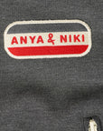Close up of a gray jacket with 'Anya & Niki' logo patch.
