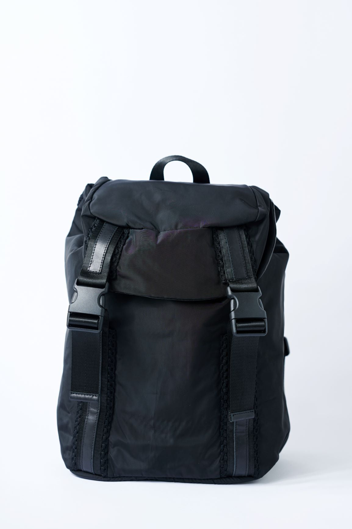 Black nylon flap top backpack with mesh and leather trim details and glossy black lining.
