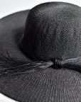 Close up of black floppy straw hat with multi-strand black cording band.