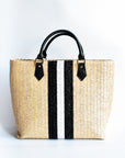 Benicia straw tote bag with black leather handles and black & white center stripe.