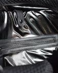 Close up of interior black glossy lining on black mesh duffel bag with leather trim details.