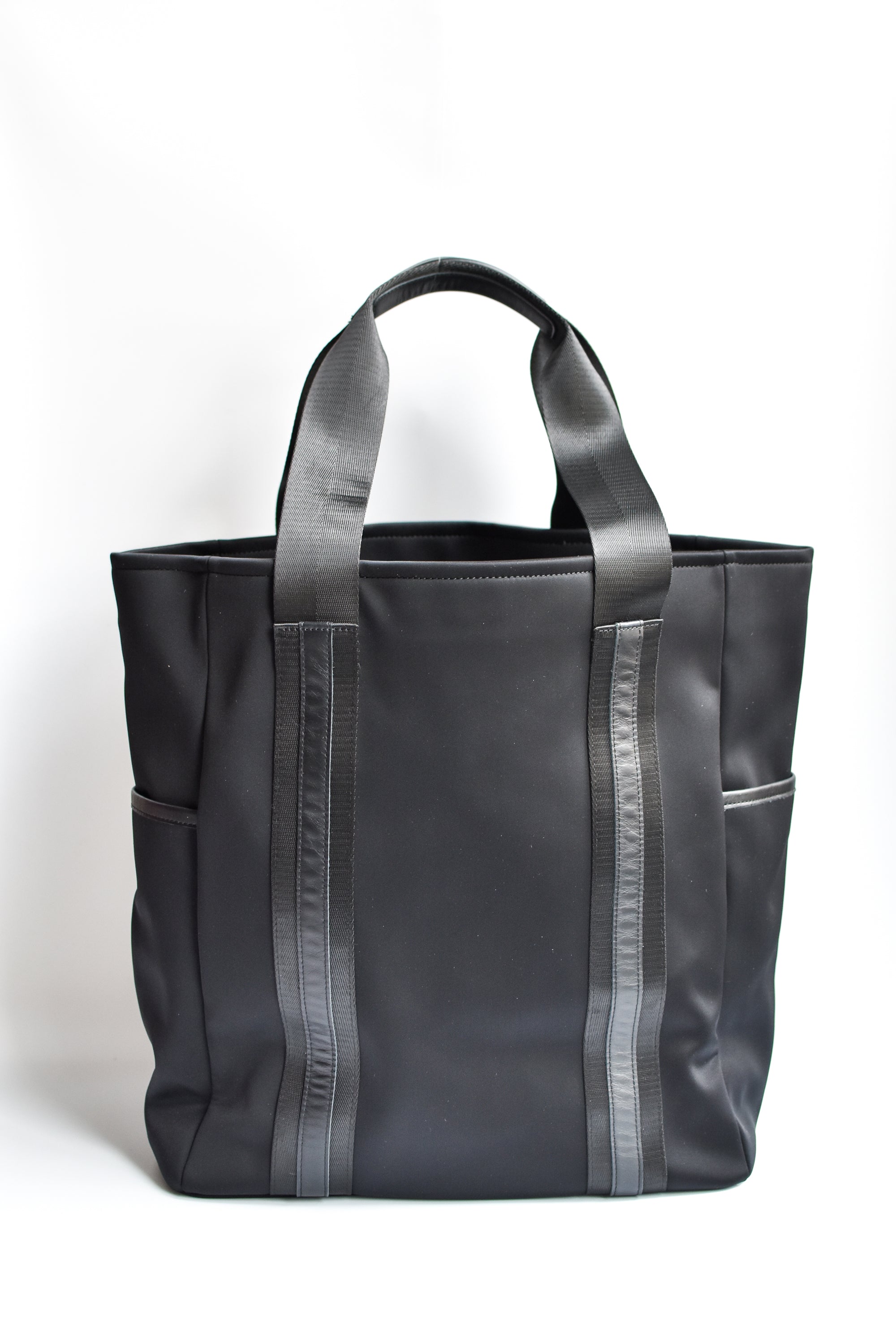 Black neoprene tote bag with high shine cinch top closure and leather details.
