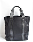 Black neoprene tote bag with high shine cinch top closure and leather details.