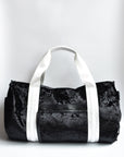 Black velour duffel bag with white straps and leather details.