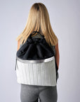 Person wearing black & white nylon cinch top backpack with signature leather and shiny silver details.