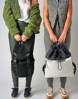 Two people holding Anya & Niki backpacks, including the Newberry black mesh backpack and the Pace black & white nylon cinch top backpack.