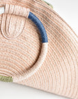 Pink half-moon straw clutch with colorful wrapped circle handle and leather sides.