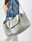 Person holding the Callahan light gray perforated neoprene duffel bag with leather details.
