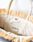 Close up of interior linen lining on natural raffia straw tote with gray color block base.