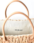 Close up of tan leather handles on large natural hyacinth straw tote.