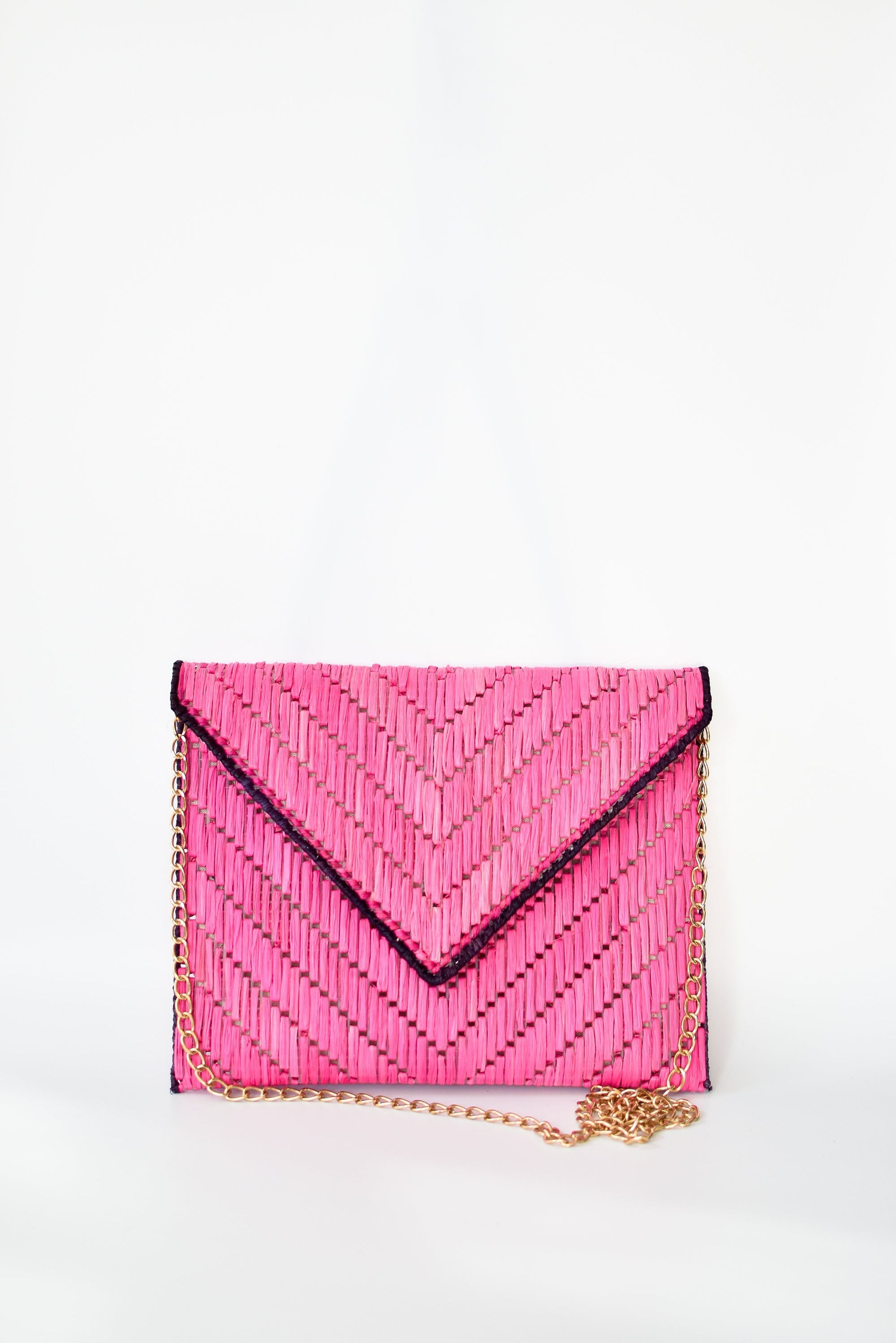 Bright pink woven raffia straw clutch with detachable gold chain strap.