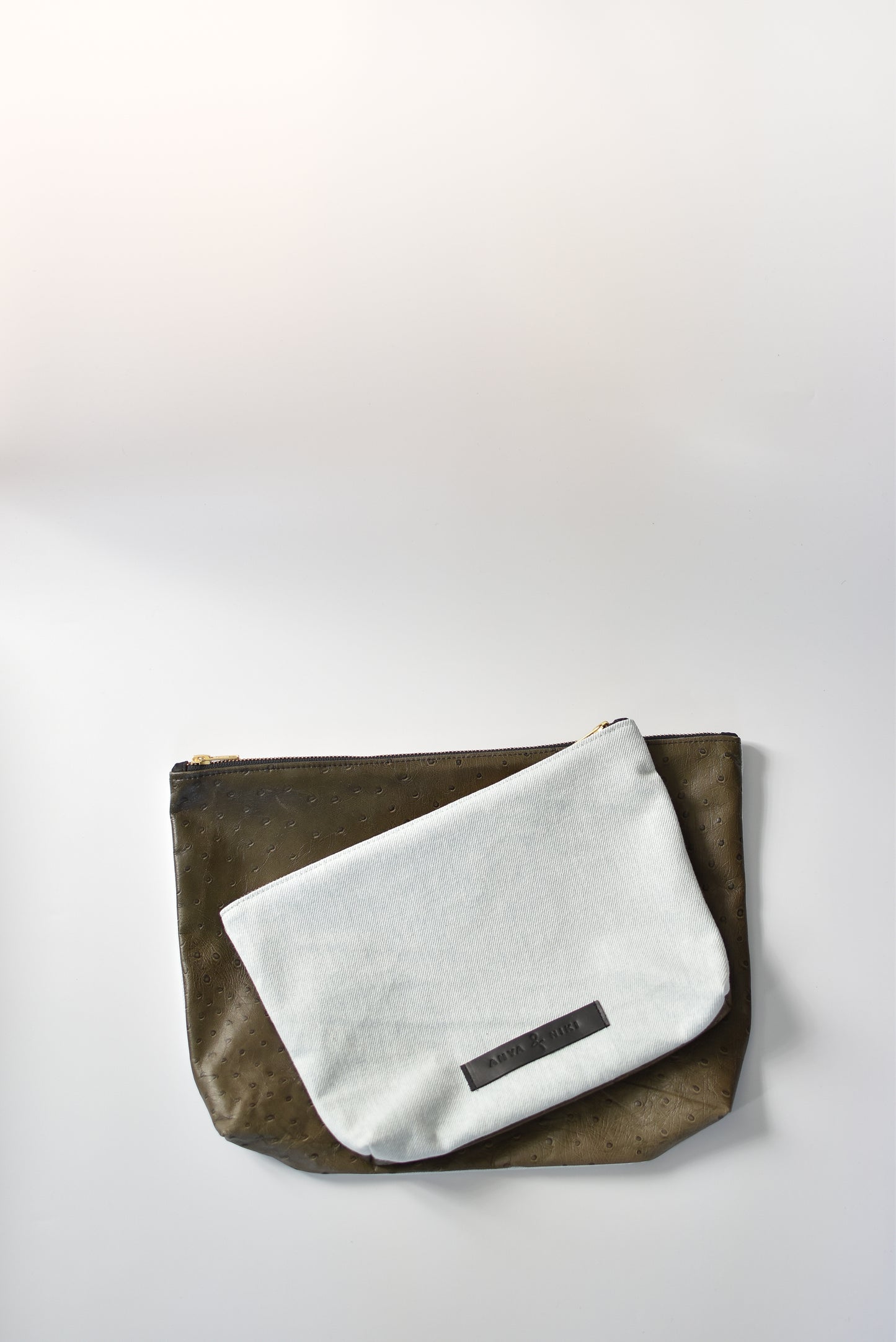 Bleached denim and fern colored embossed leather skin medium and large pouch with brass zipper and leather logo label.