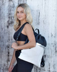 Person wearing black & white nylon cinch top backpack with signature leather and shiny silver details.