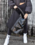 person with black mesh and glossy vinyl sporty tote bag with black leather and webbing details.
