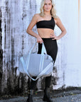 Person holding the Callahan light gray perforated neoprene duffel bag with leather details.