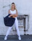 Person holding large puffy navy nylon tote bag with crossbody strap