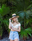 Person wearing raffia straw panama hat with black grosgrain tie