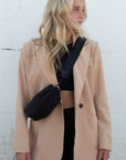 Person wearing black nylon belt bag with black crossbody strap with black leather detail