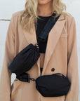 Person wearing two black nylon belt bag with black crossbody strap