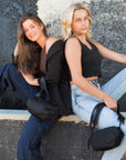 Two people sitting holding the Anya & Niki Orlando Black Belt Bag: one with black leather detail and one with shiny black leather detail,