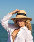 Person wearing raffia straw panama hat with black grosgrain tie