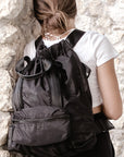 Person wearing the Anya & Niki Davie Backpack - a black nylon convertible backpack tote with leather details.