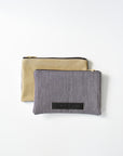 Railroad striped denim and taupe colored leather small pouch with brass zipper and leather logo label.