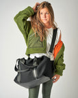 Person wearing the Anya & Niki Stanton Bag - a black mesh duffel bag with leather trim details and black glossy liner.
