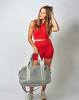 Person holding the Callahan light gray perforated neoprene duffel bag with leather details.