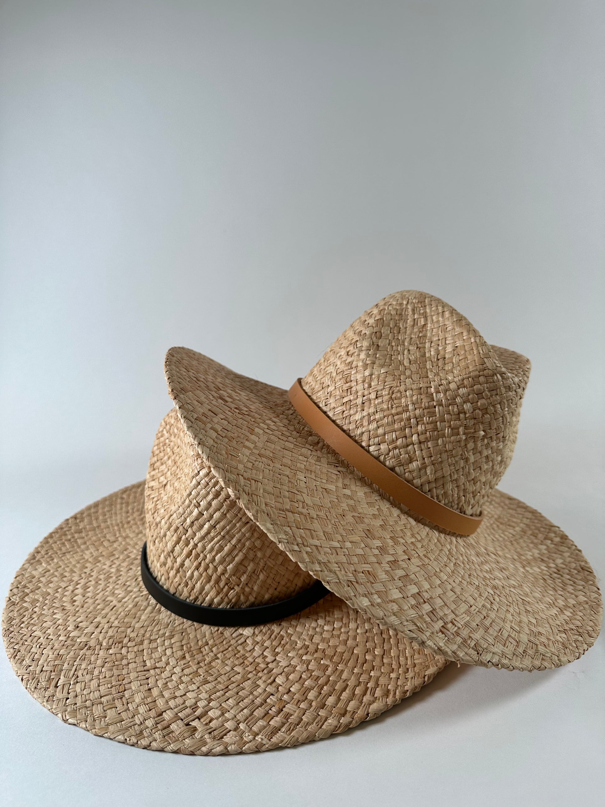 Stack of new Straw panama hats with leather bands, one tan on black. 