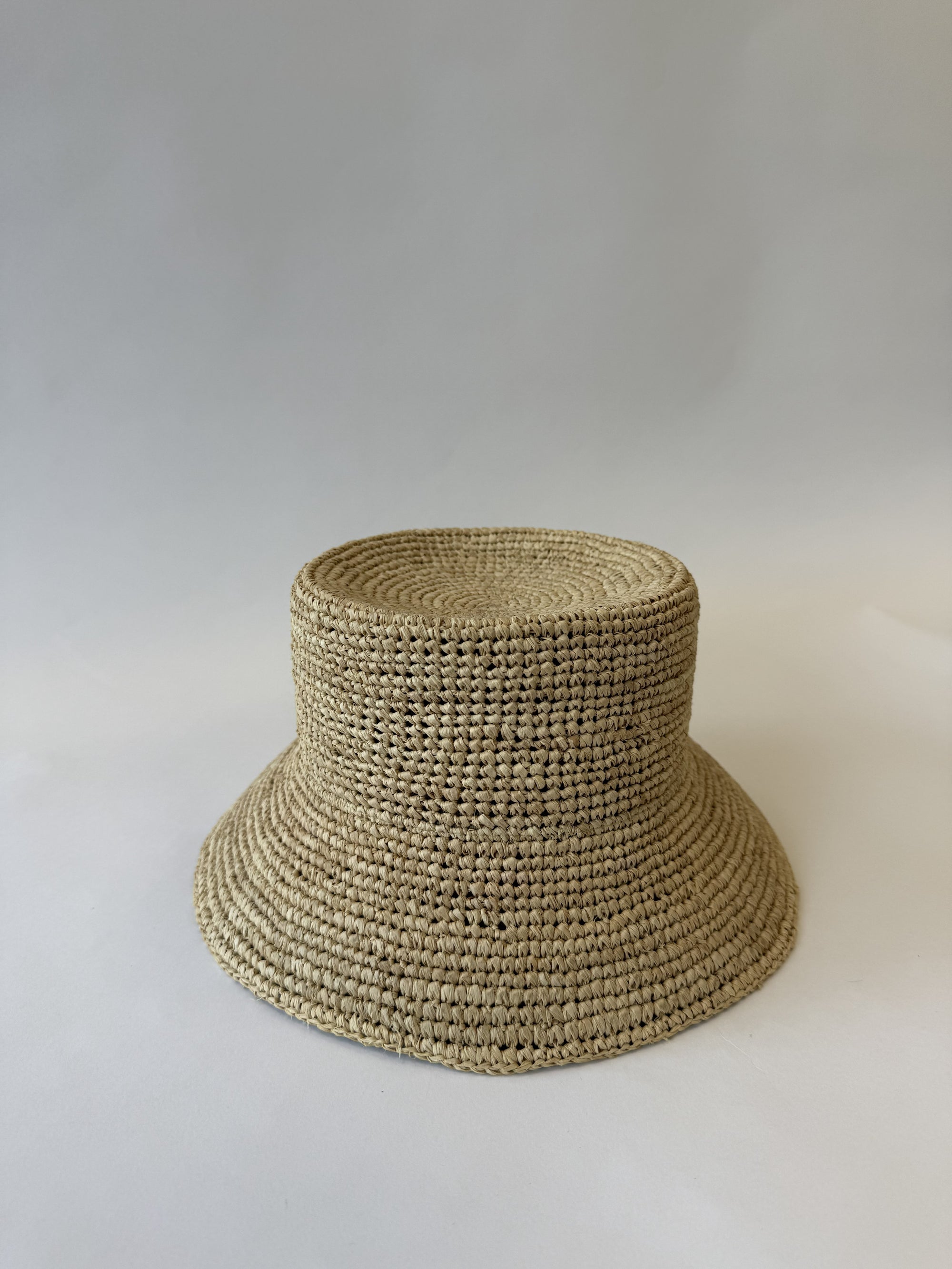 Woven straw bucket hat on a plain background