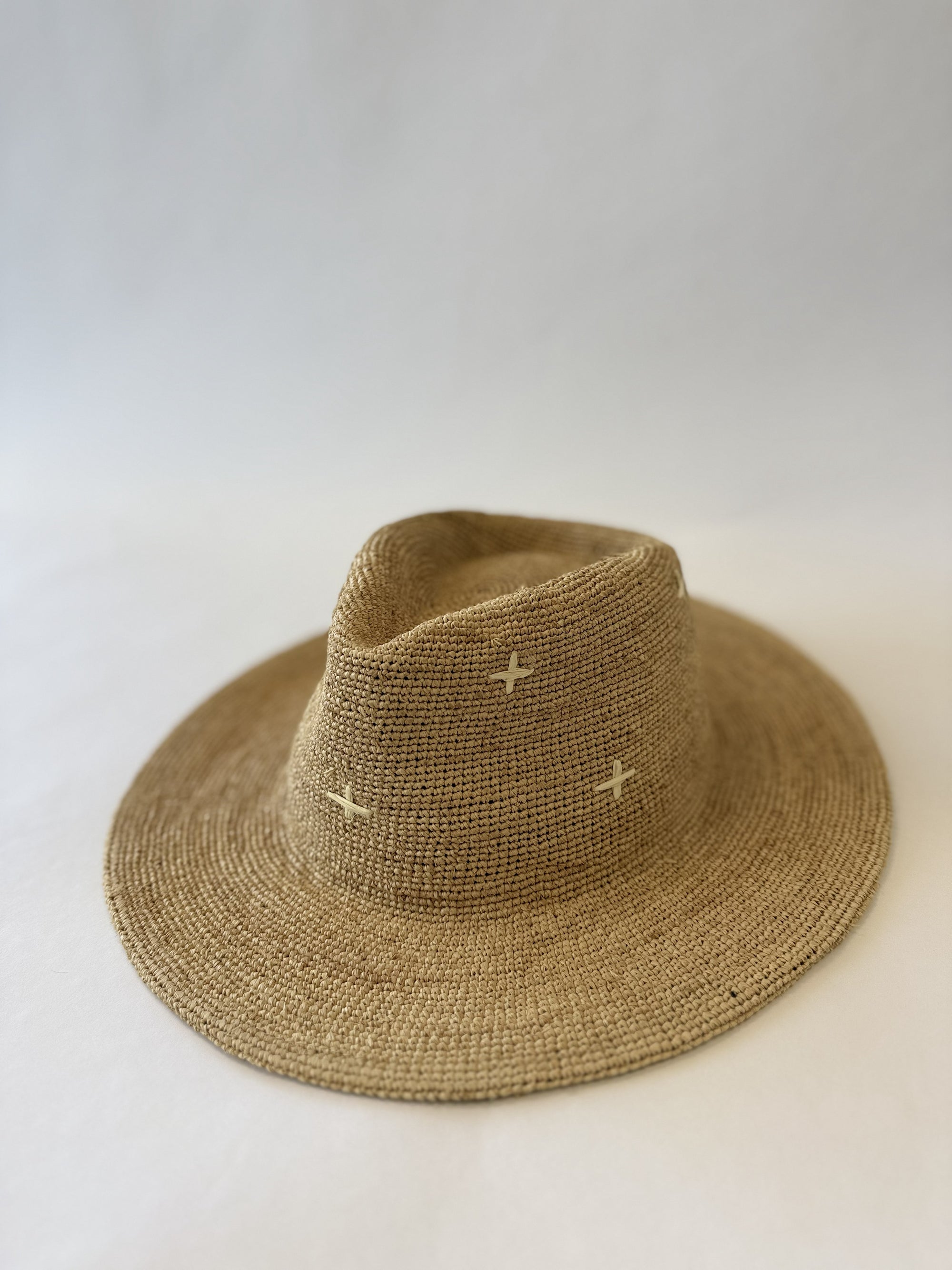 Brown straw hat with small white patterns on a light gray background