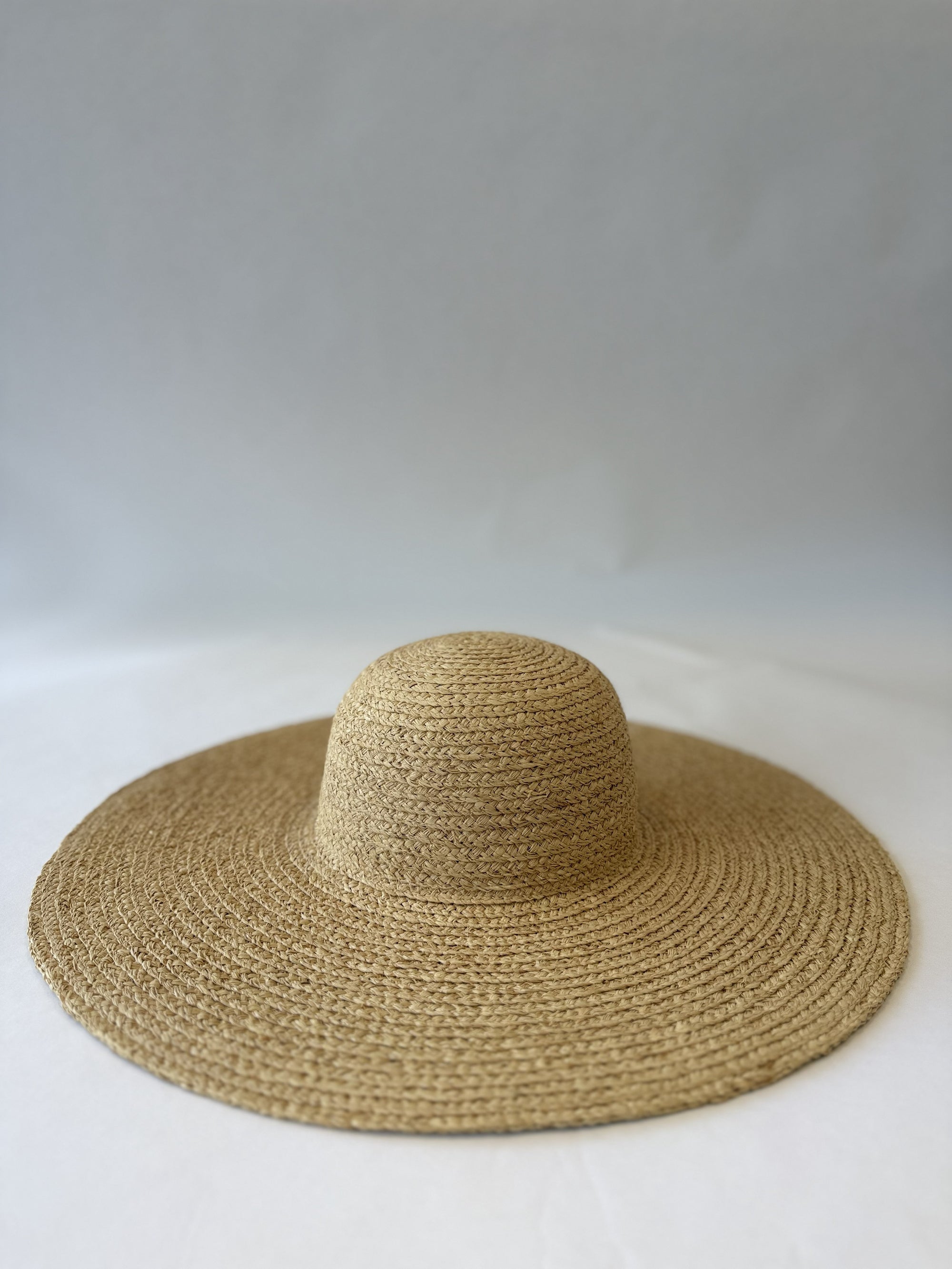 Beige straw floppy hat on a white background