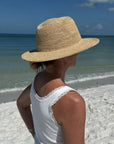 Person wearing a straw hat and white sleeveless top on a beach