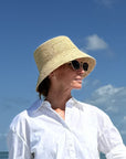 Person wearing a straw hat and sunglasses against a blue sky.