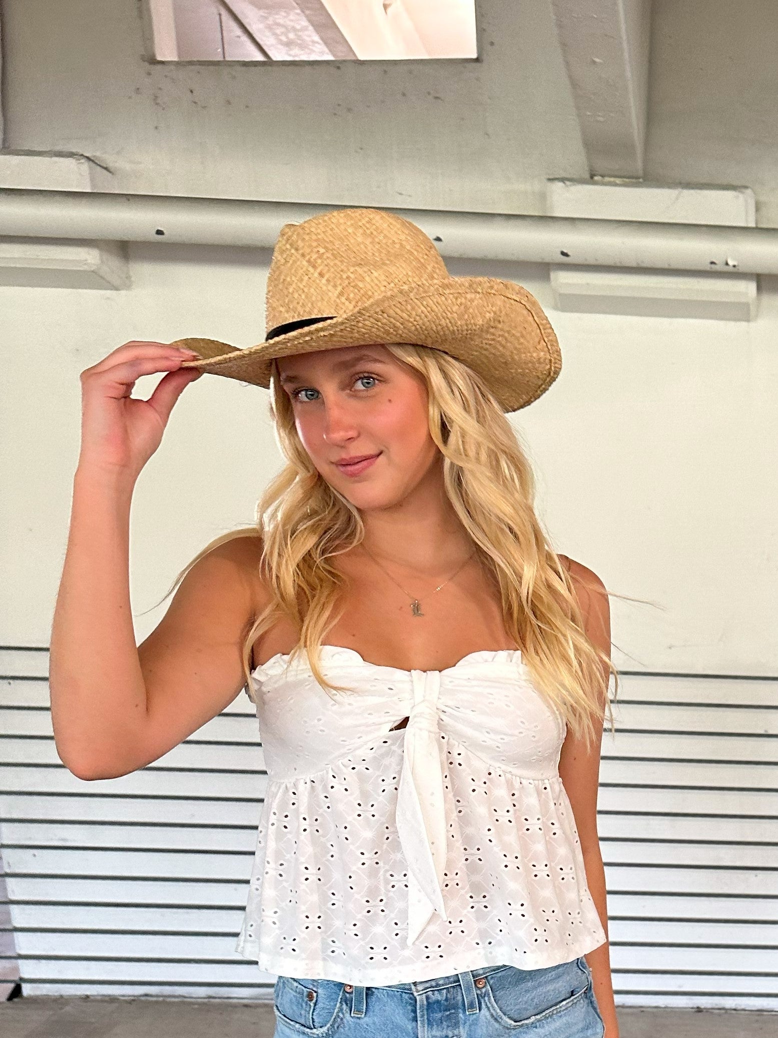 Person wearing the Raffie Straw Western Hat with black leather band