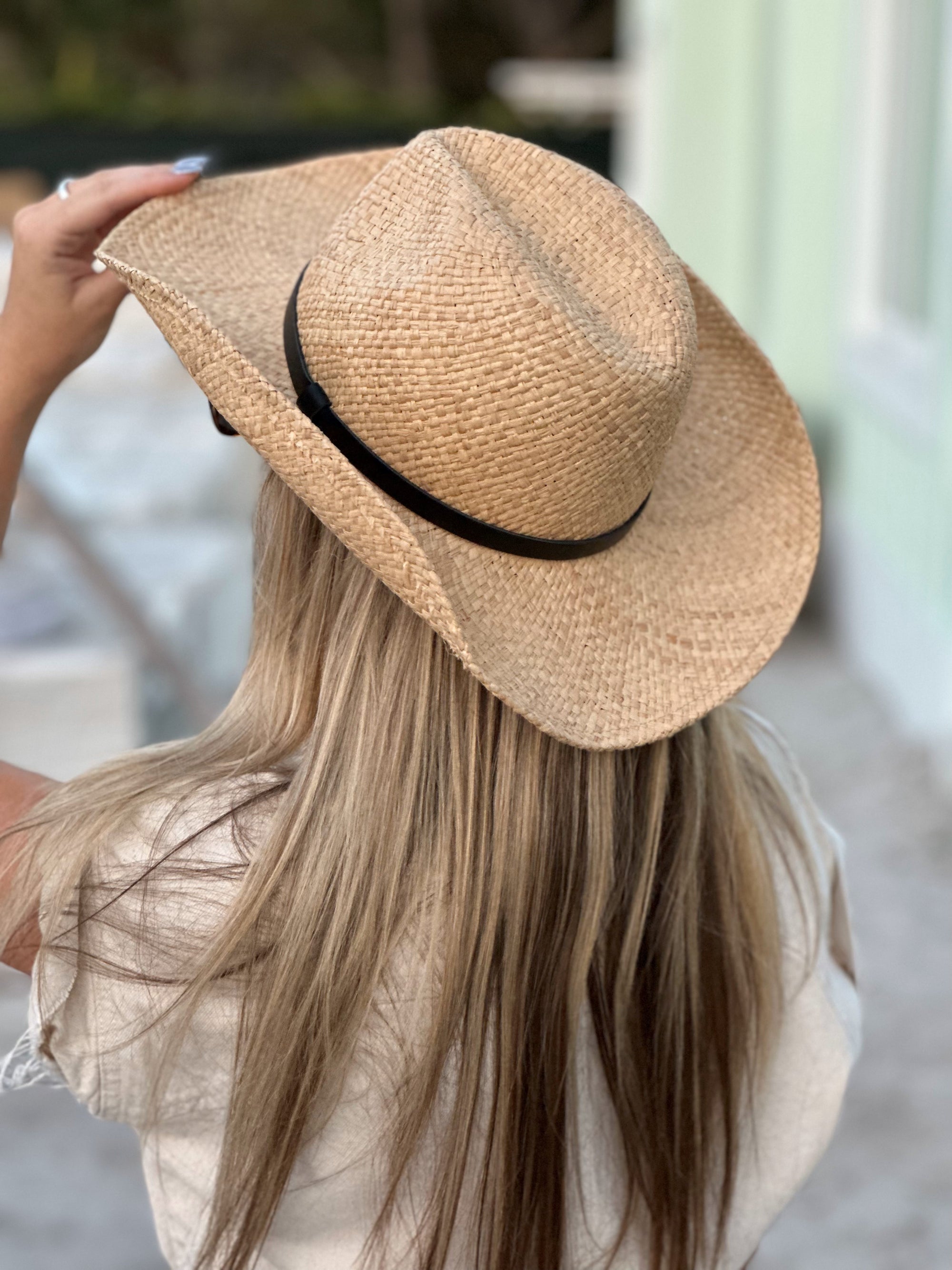 Person wearing the Raffie Straw Western Hat with black leather band