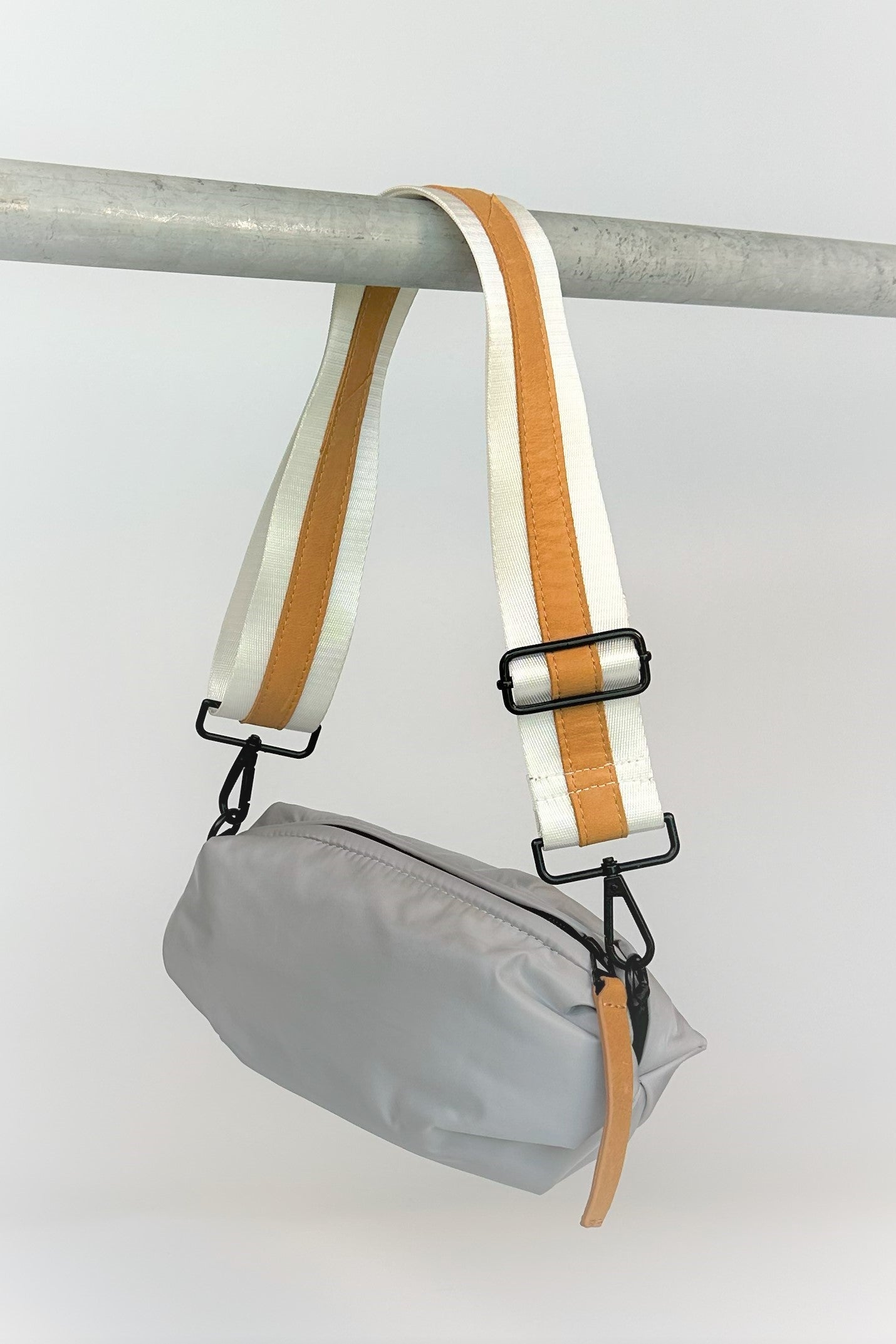 Gray nylon belt bag with white crossbody strap and tan leather detail
